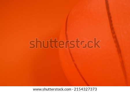 a plastic soccer ball with black stripes on orange, orange background