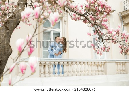 Luxury couple posing under blooming magnolia tree. Vintage villa at background
