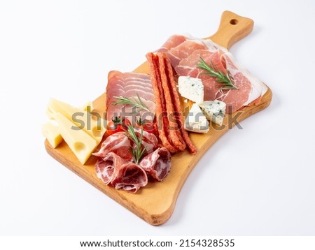 Mixed delicatessen with charcuterie and cheese board with a place for text. Italian appetizers or antipasto set with gourmet food on wooden cutting board isolated on white background. Royalty-Free Stock Photo #2154328535