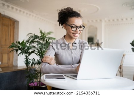 The administrator is a woman working in a modern office using a laptop computer communicating online video communication with colleagues.