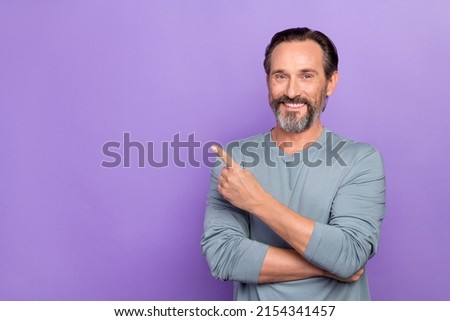 Photo of handsome guy pointing finger empty space promote cool product isolated on violet color background