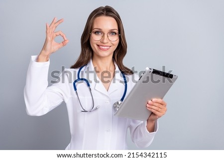 Photo of young woman cardiologist use modern device show fingers okey symbol recommend isolated over grey color background