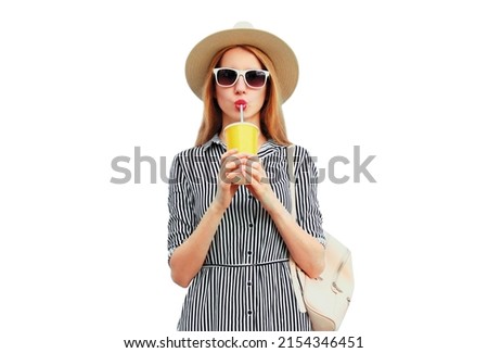 Portrait of beautiful young woman drinking fruit juice wearing summer round straw hat, striped dress isolated on white background