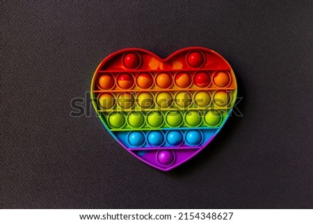 Pop it fidget toy on black background. Rainbow heart anti stress fidget. Valentines day concept. heart - symbol of love