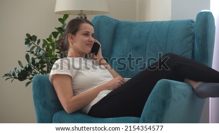 Authentic Young Woman Chatting On Phone In Living Room. Writing Searching Using IT. Happy Lady Working On Smartphone Browsing Internet On Comfortable Easy Chair. Business, Education, Technology Concept
