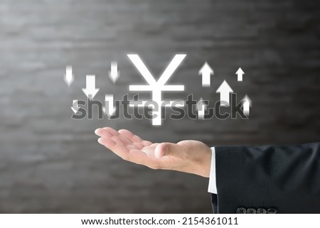 Business man's hand and Japanese yen mark with upward and downward arrows