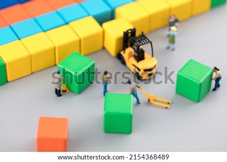 Miniature creative laborer carrying building blocks