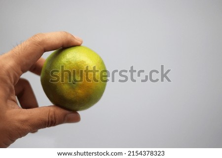 yellow-green sapphire orange fruit in hand