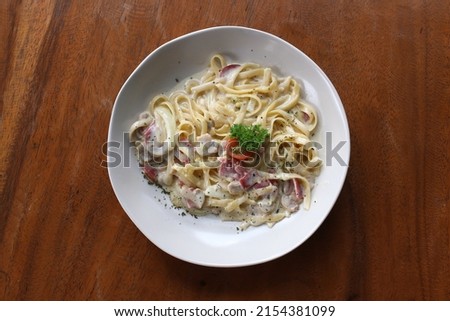 Carbonara served on white plate in wooden table