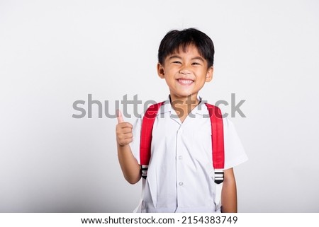 Asian adorable toddler smiling happy wearing student thai uniform red pants show thumb up finger in studio shot isolated on white background, Portrait little children boy preschool, Kid Back to school Royalty-Free Stock Photo #2154383749