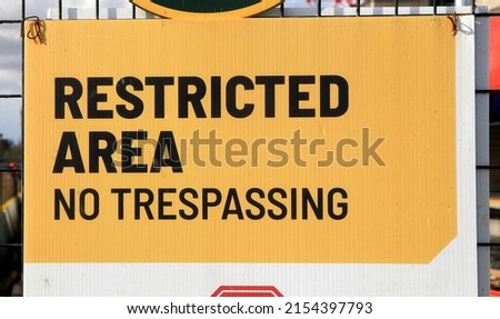"Restricted Area No Trespassing" yellow construction sign. 

 Royalty-Free Stock Photo #2154397793