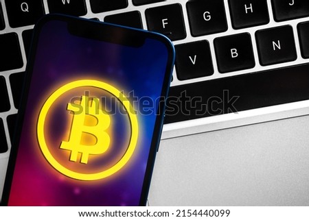 Bitcoin logo on mobile phone, laptop background