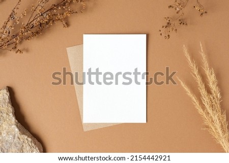 Blank greeting card, invitation mockup. Dry grass, pampas plant on beige table background. Flat lay, top view. Copyspace. Paper cards, mock up. Modern Minimal business brand template. Soft shadow, A6