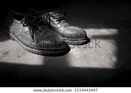 closeup of a pair of worn selective shoes in black and white concept on the ground, with the reflection of the sun. shoe vintage concept