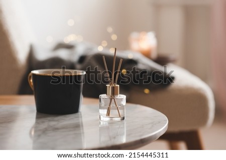Bamboo sticks in bottle with scented candles and cup of tea on marble table closeup. Home aroma. Aromatherapy. Apartment living.  Royalty-Free Stock Photo #2154445311