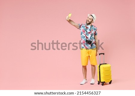 Full length of laughing young traveler tourist man in summer clothes hat doing selfie shot on mobile phone isolated on pink background. Passenger traveling on weekends. Air flight journey concept Royalty-Free Stock Photo #2154456327