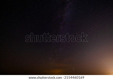 From below spectacular dark sky with orange clouds and many stars at night in nature Royalty-Free Stock Photo #2154460169