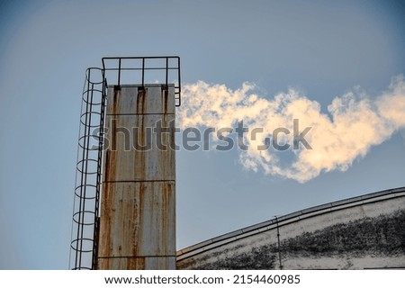 Factory chimney against the blue sky polluting the environment