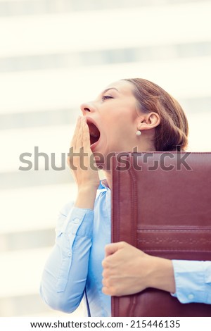 Its is too early for this meeting. Closeup portrait sleepy young business woman, running to work wide open mouth yawning, eyes closed looking bored isolated outside corporate office windows background
