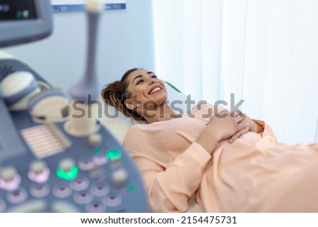 Happy pregnant female visiting women's doctor in the maternity center, doing ultrasound scan, worried about the health of the child, healthy motherhood concept Royalty-Free Stock Photo #2154475731
