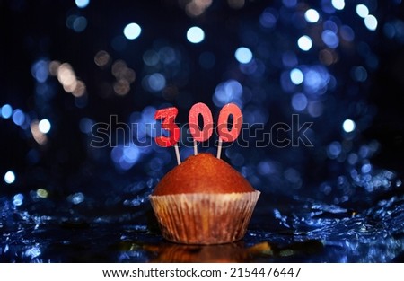 Tasty homemade vanilla anniversary cupcake with number 300 three hundred on aluminium foil and blurred bright background in minimalistic style. Digital gift card birthday concept. High quality image
