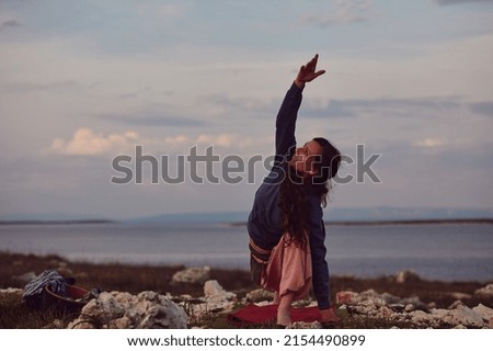 Woman practicing yoga outdoors in sunset sunrise time.