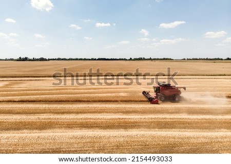 Harvester harvests in the field, drone view. Red Combine harvester collects wheat taken from a drone. Royalty-Free Stock Photo #2154493033