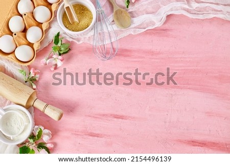 Bakery  or cooking frame with flowers, ingredients, kitchen items for pastry on pink background,  spring cooking theme. Top view, copy space. Royalty-Free Stock Photo #2154496139