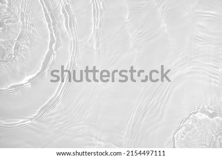 Desaturated transparent clear water surface texture with ripples, splashes Abstract nature background. White-grey water waves overlay Copy space, top view. Cosmetic moisturizer micellar toner emulsion Royalty-Free Stock Photo #2154497111