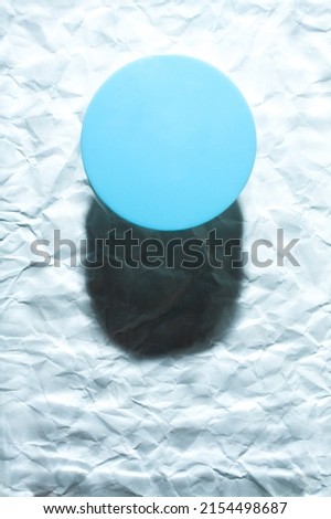 Round blue object on abstract blue background. Minimalist flat lay single object with shadow.