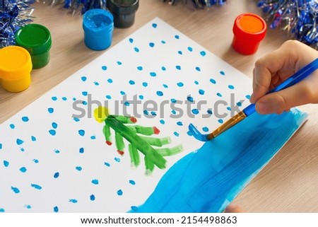A child draws a Christmas tree. Ideas for drawing with bright colors. Drawing children on a white background. A little girl draws with paint and brushes. The concept of children's development