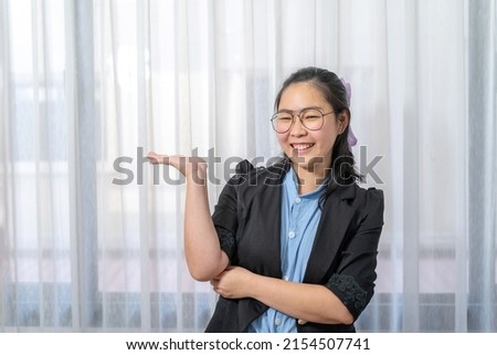 Asian happy woman opens hands palm up showing and holding empty or something with confidential on black copy space for production and information.