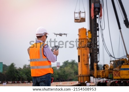 Engineer construction used drone take photo aerial view for inspection and survey at construction site drilling pile under work industrial with crane background.
