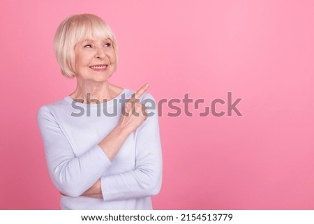 Photo of pretty retired woman look indicate finger empty space promotion follow advertising isolated over pink color background