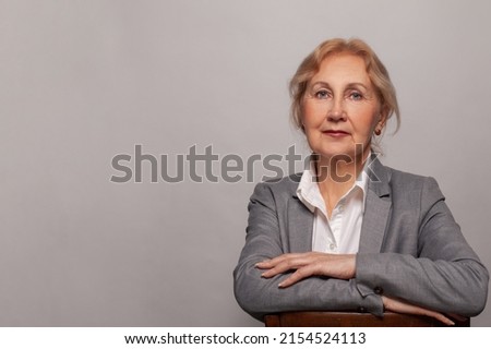 Smiling beautiful mature business woman on white background. Older senior businesswoman, 60s lady professional female ceo, coach looking at camera on studio wall banner with copy space.