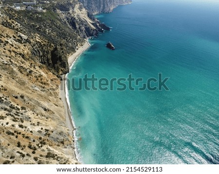 Aerial view on calm azure sea and volcanic rocky shores. Small waves on water surface in motion blur. Nature summer ocean sea beach background. Nobody. Holiday, vacation and travel concept