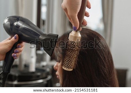 Professional stylist making hairstyle using hair dryer and brush Royalty-Free Stock Photo #2154531181