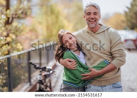 Teenage daughter hugging her father outside in town when spenidng time together.