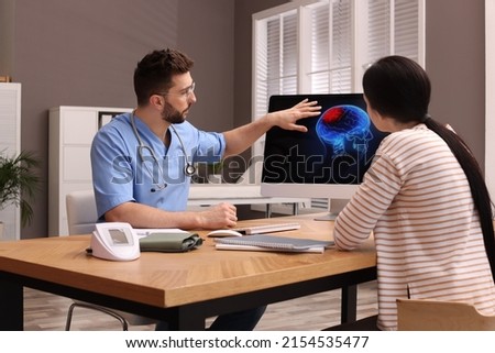 Neurologist showing brain scan to young woman in clinic Royalty-Free Stock Photo #2154535477