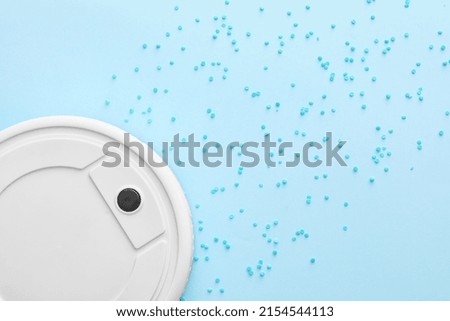 Modern robot vacuum cleaner and sprinkles on blue background