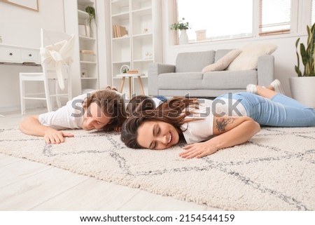 Happy young family lying on soft carpet at home Royalty-Free Stock Photo #2154544159