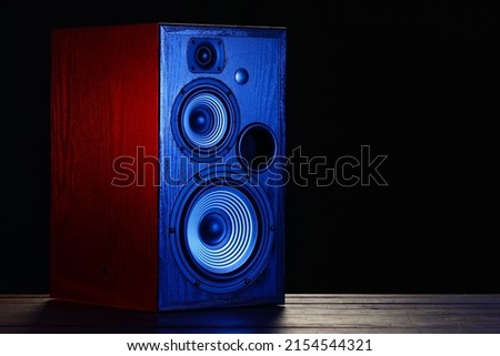 Modern loudspeaker on table against black background Royalty-Free Stock Photo #2154544321