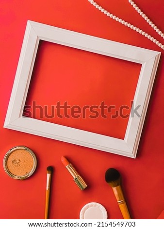 White horizontal art frame, make-up products and pearl jewellery on orange background as flatlay design, artwork print or photo album concept