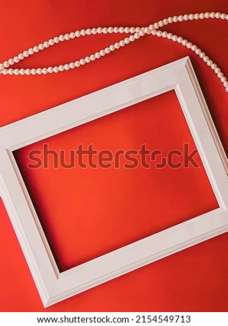 White horizontal art frame and pearl jewellery on orange background as flatlay design, artwork print or photo album concept