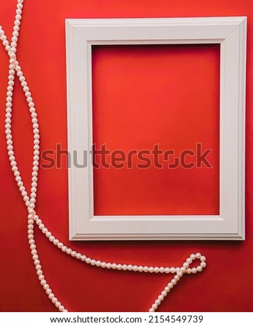 White vertical art frame and pearl jewellery on orange background as flatlay design, artwork print or photo album concept