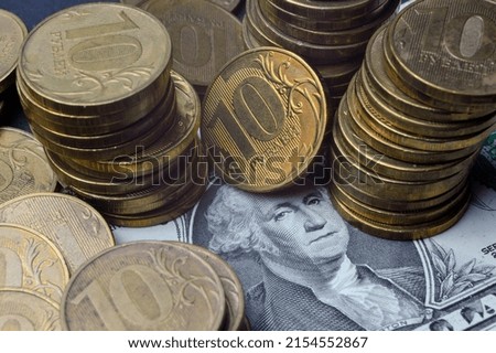 The American dollar on top of which lie Russian coins with a face value of 10 rubles. Translation of the inscriptions on the coins: "10 rubles". close-up