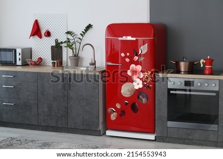 Red refrigerator with print of leaves and flowers in interior of modern kitchen