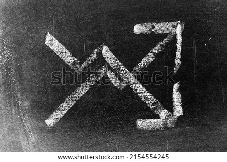 White color chalk hand drawing in up and down arrow shape on black board background