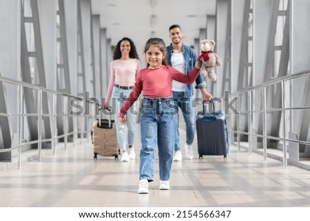 Portrait Of Joyful Cute Middle Eastern Girl Walking At Airport With Parents, Happy Young Arabic Family Ready For Vacation Trip Together, Going To Departure Gate At Terminal, Selective Focus On Kid Royalty-Free Stock Photo #2154566347