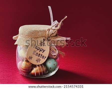 Happy Easter. Colourful painted easter eggs in glass jar on red background, Christian religion and holiday concept